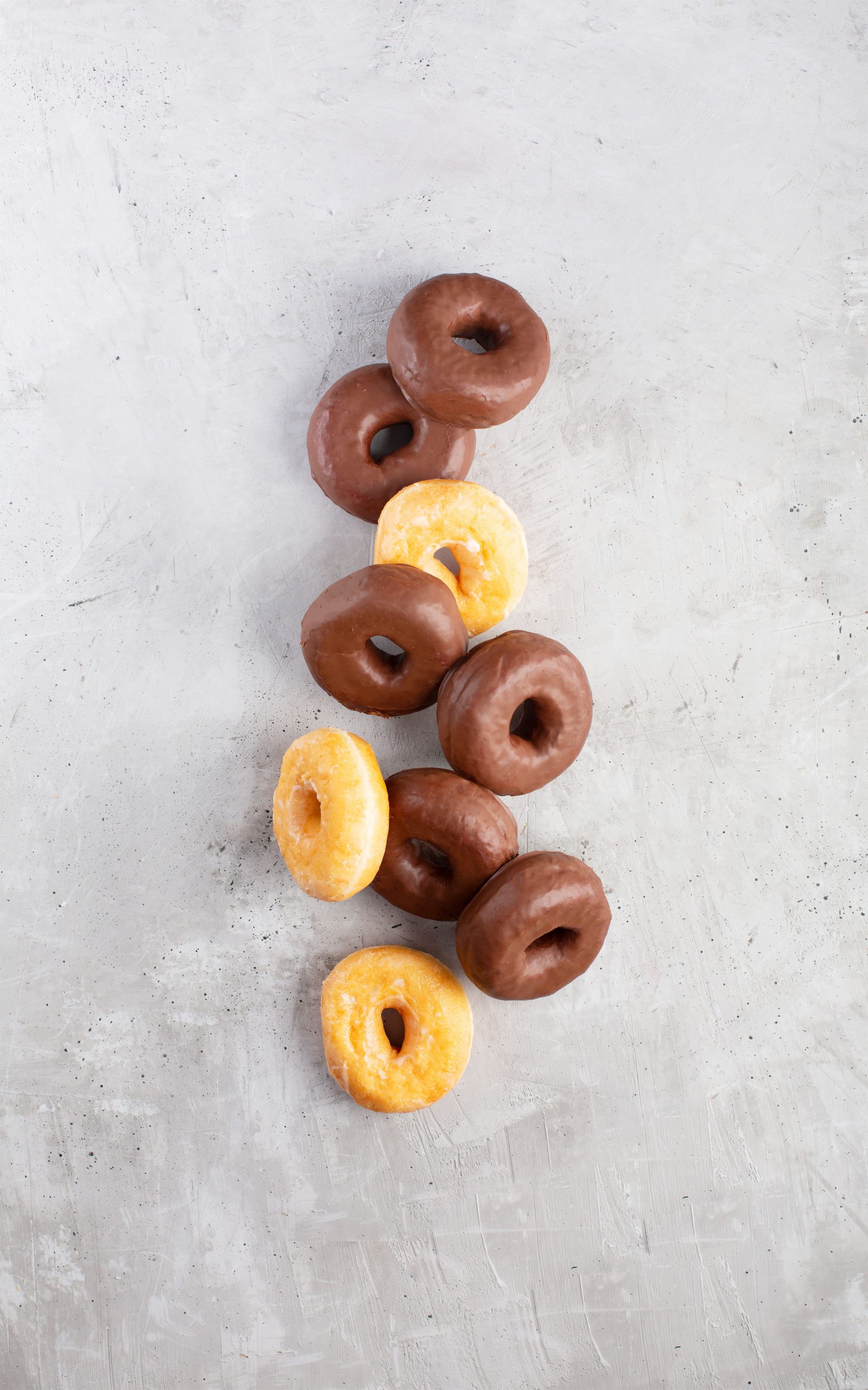 Group of glazed and chocolate donuts on gray background